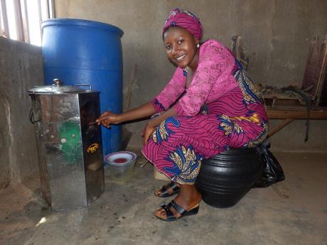 eine Frau nutzt einen Ofen aus einem Klimaschutzprojekt in Nigeria