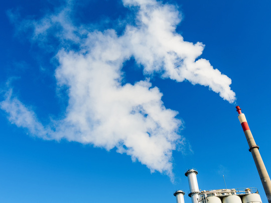 White exhaust gases rise from chimneys