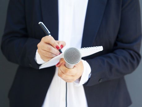 A woman holds a notepad and microphone in her hand