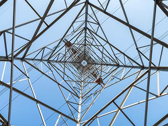 View of a power pole from below with blue sky in the background